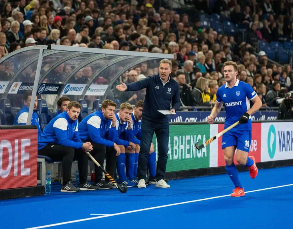 Hockeyspelers bij de wisselzone langs het veld tijdens een vliegende wissel